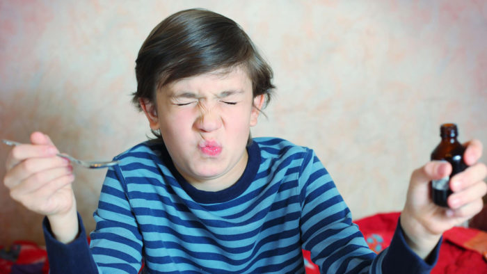 Boy grimacing at bad tasting medicine.