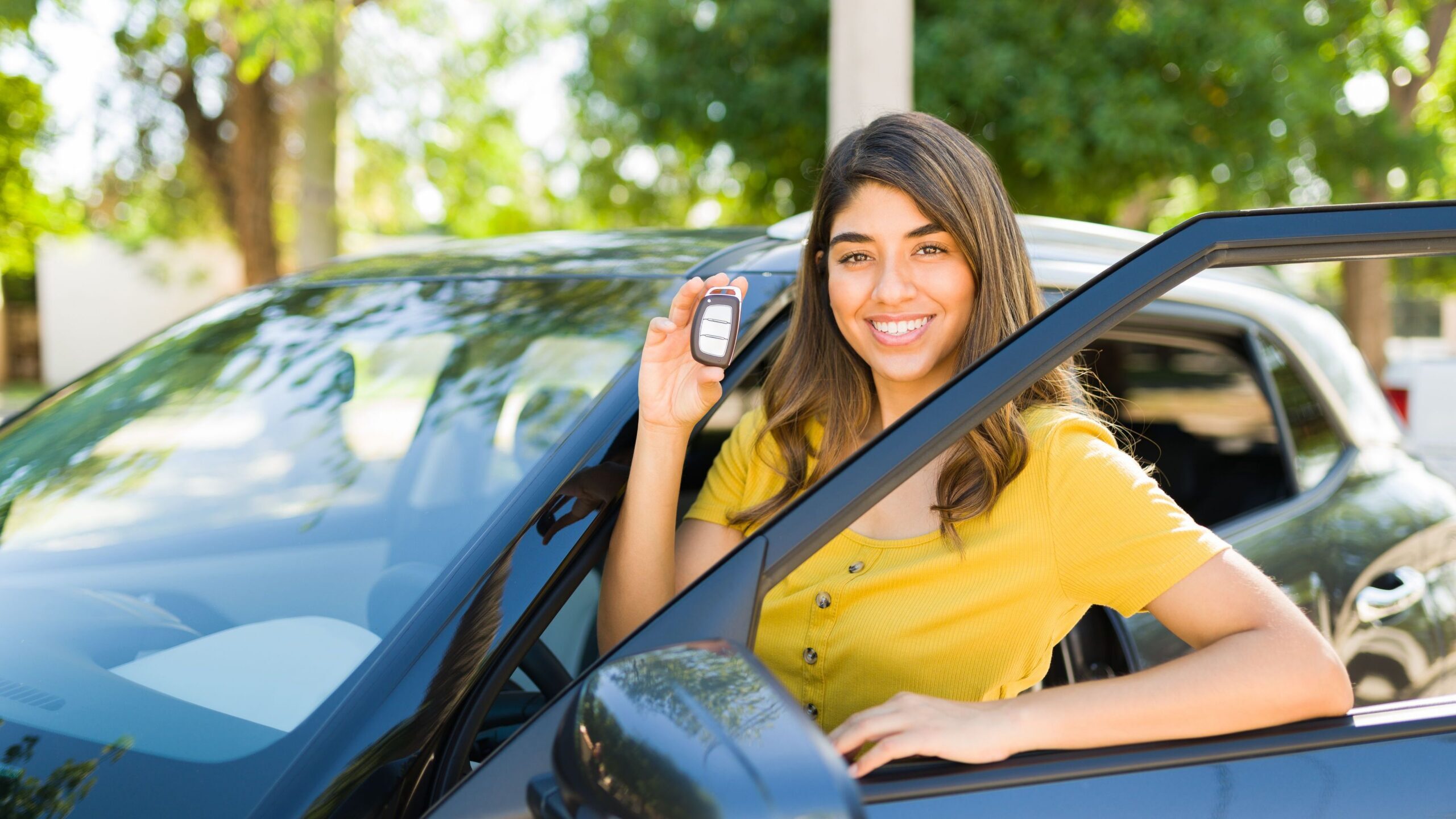 Young woman smiling after having bought her first car.
